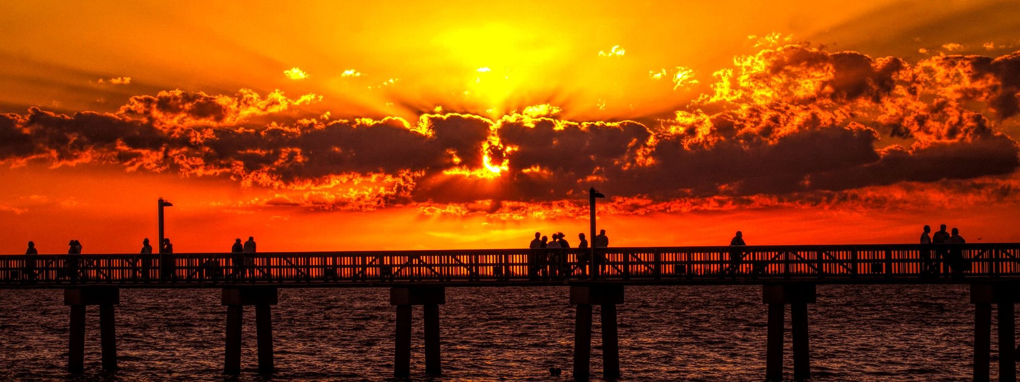 Sunset over the water in Fort Myers, with people on a pier in silhouette
